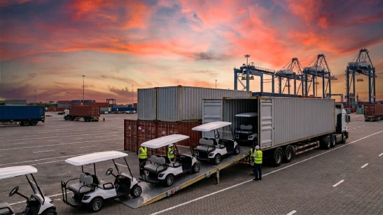 Row of white Golf Carts being loaded into a container for export